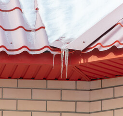 Icicles on the red roof of the house
