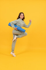 Fototapeta na wymiar happy child in sportswear running with fitness mat. fit your body.