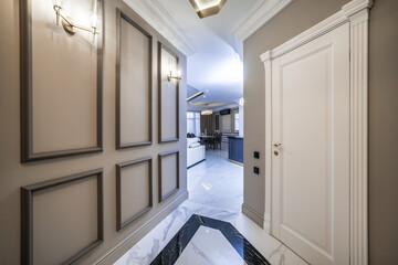 Entrance corridor in a new apartment with a fresh renovation in a minimalist style. Beige-brown tones, marble floors
