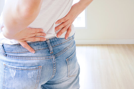 woman in white t-shirt touch her waist and hold lower back and hip and bend the back which suffering from back pain or back ache with copy space