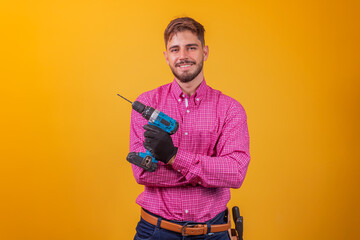 Positive and confident repairman in a plaid shirt and a tool kit on his hip and an electric screwdriver smiling and looking at the camera