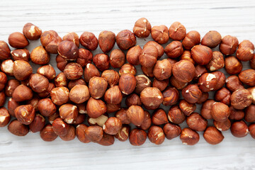 Unshelled Hazelnut in a Bowl on a white wooden background, top view. Flat lay, overhead, from above.