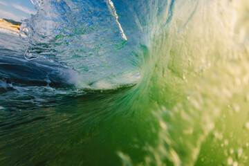 Perfect surfing swell in ocean. Barrel wave with morning warm light
