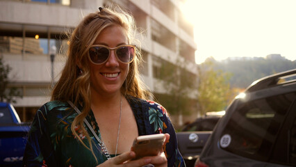 Smiling Blonde Woman in her twenties on smartphone texting in city