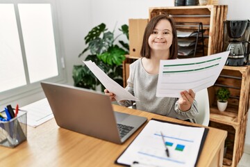 Brunette woman with down syndrome working looking at documents at business office