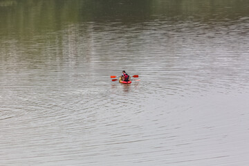 View of two young women with paddles in their hands in canoe, with life jackets, practicing canoeing on the Guadalquivir River in Cordoba, Spain