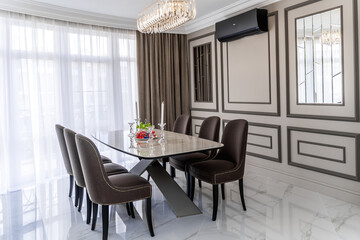 Oval light modern table and chairs with dark upholstery.