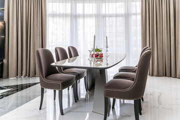 Oval light modern table and chairs with dark upholstery.