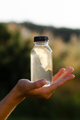 Transparent bottle with water and lemon on hand.
