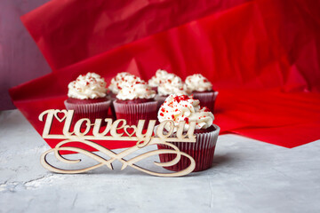View of red velvet cupcakes and wooden lettering "I love you". Romantic dessert.