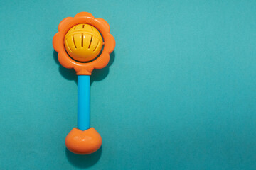Orange bright baby rattle on a blue background for the development of motor skills in children. Copy space