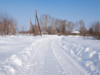 Winter rural road and trees in snow and sun at sunset.