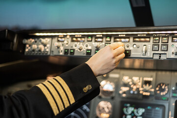 Close-up of a pilot's hand on an airplane control panel.