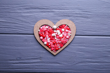 Obraz premium Heart of candy in wooden form on a grey background