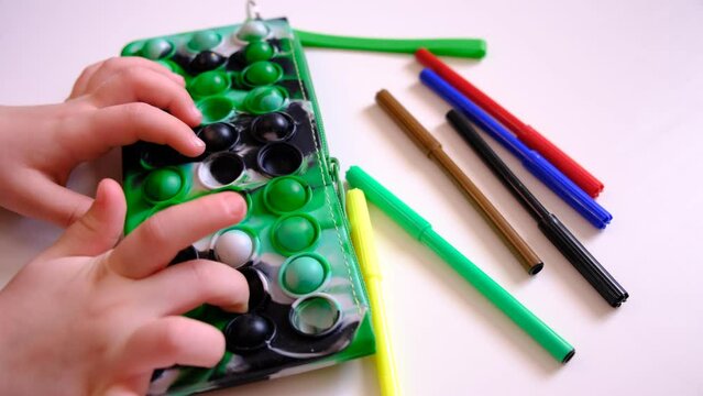 Child with a modern  push pop fidget toy, pencil box. Simple dimple. Child with  trendy antistress silicon sensory toy