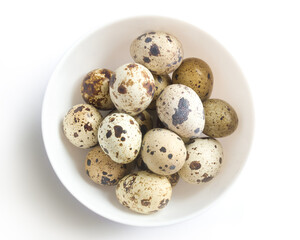 Quail eggs in a white bawl. Isolated on white background. Top view.