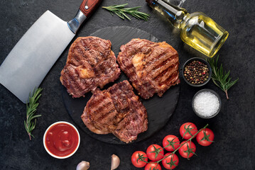 three grilled beef steaks with spices on a stone background