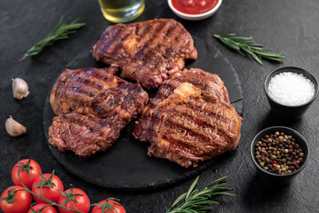 three grilled beef steaks with spices on a stone background