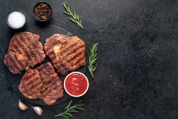 three grilled beef steaks with spices on a stone background with copy space for your text