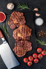 three grilled beef steaks with spices on a stone background
