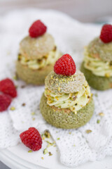 Choux with pistachio cream and raspberry french dessert on white background close up selective focus