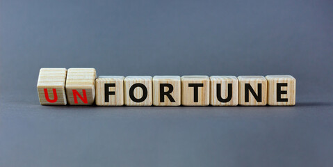 Fortune or unfortune symbol. Turned wooden cubes and changed the concept word unfortune to fortune. Beautiful grey table, grey background, copy space. Business, fortune or unfortune concept.