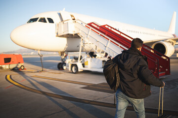 Passenger walking with his suitcases towards the plane