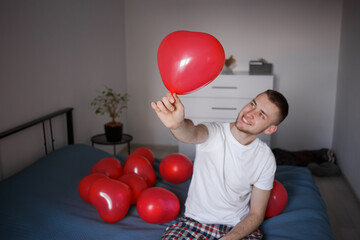 The guy holds a balloon in the form of a heart, for Valentine's Day
