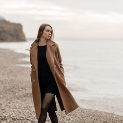 portrait of a young happy woman in coat and glasses outdoor on the beach autumn spring