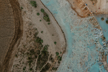 Obraz premium The aerial drone view of people swimming and relaxing in Saturnia hot springs in Tuscany, Italy. Nature, hot spring lagoons, lush forests and fields on a hot summer day