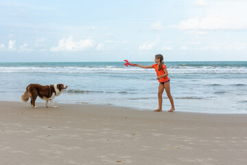 Criança brincando na praia com cachorro Colie