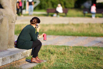 Kobieta z czerwoną puszką napoju rozmawia przez telefon. - obrazy, fototapety, plakaty