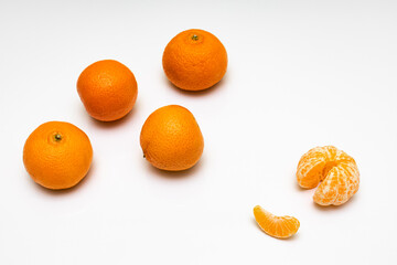 peeled tangerine lies on the background of other unpeeled tangerines