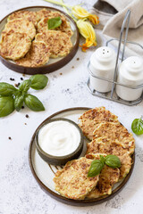 Zucchini fritters. Vegetarian zucchini pancakes with cheese, served with sour cream on a rustic wooden table. Healthy food, low calories keto dieting meal.