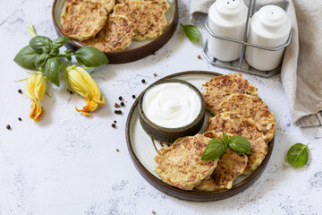 Zucchini fritters. Vegetarian zucchini pancakes with cheese, served with sour cream on a rustic wooden table. Healthy food, low calories keto dieting meal. Copy space.