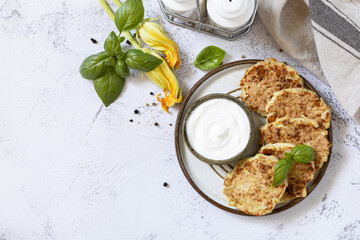 Zucchini fritters. Vegetarian zucchini pancakes with cheese, served with sour cream on a rustic wooden table. Healthy food, low calories keto dieting meal. Copy space.
