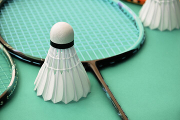 Cream white badminton shuttlecock and racket on floor in indoor badminton court, copy space, soft and selective focus on shuttlecocks.