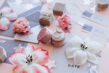 Layout with Wedding day spelled in wooden blocks, statuette of two lovely angels, giftbox, rings, postcards, heart shaped frame and white peonies on the wooden table. Invitation, greeting concept