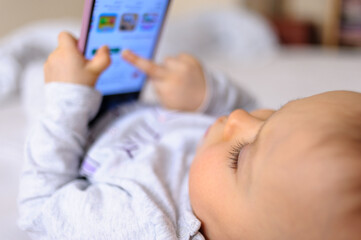 Baby holding a mobile phone and playing with touchscreen
