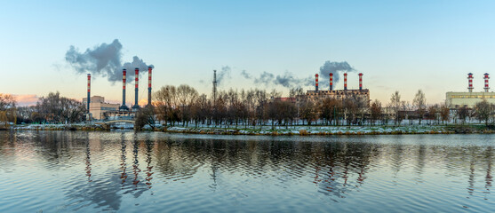 Smoking chimneys of a thermal power plant against a winter cloudy sky. Ecological problems concept. Space for text.