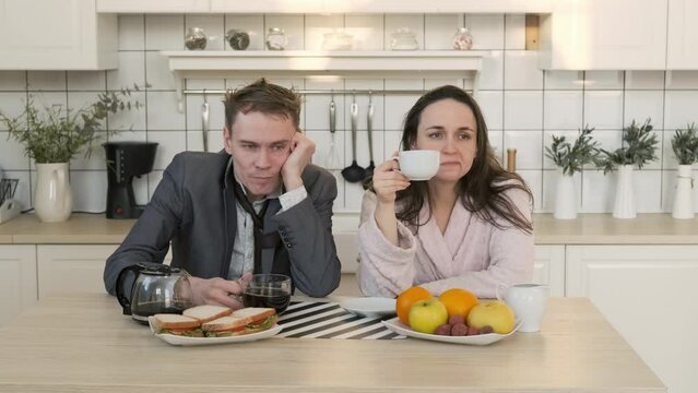 Exhausted Male and his Wife Drinking Coffee in the Morning at Home. Man Looks Disheveled and Untidy after Sleepless Night. Business, Lifestyle, Overworking Concept