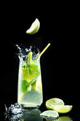 A slice of lime falling into a glass. A piece of lemon falling into a cocktail. A piece of lemon in the air.
