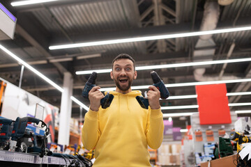 Fototapeta na wymiar happy and cheerful customer with two screwdriver and in his hands in a hardware store