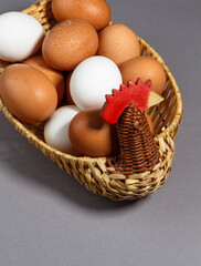Chicken and a basket with eggs isolated on gray background.