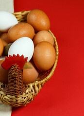 Chicken and a basket with eggs isolated on red background. vertical