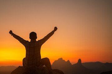 Silhouette of success man hiker outstretched arms on top of the mountain with beautiful sunset.Concept of adventure travel