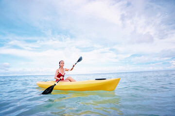 Young woman paddling the sea kayak in thel calm lagoon.