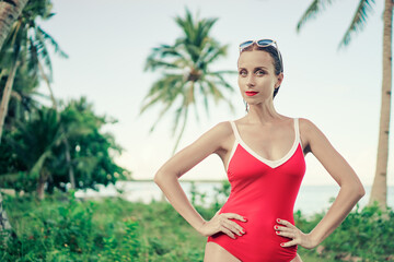 Vacation on the seashore.Young woman in red swimsuit on the beautiful tropical beach with palm trees.