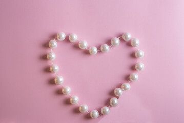 frame in the form of a heart made of pearls on a pink background with a place for an inscription
