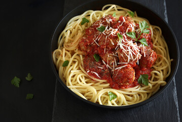 Spaghetti con polpette al sugo di pomodoro su fondo scuro. Direttamente sopra.